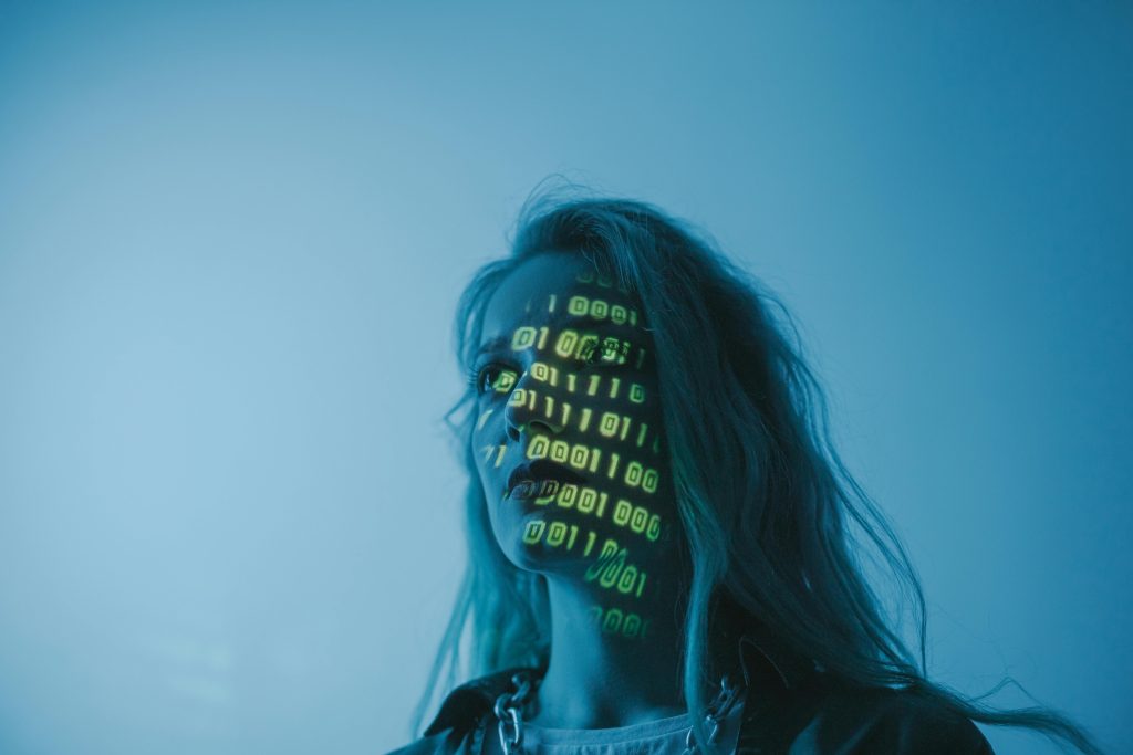 pexels-photo-5473955-5473955 A woman with binary code lights projected on her face, symbolizing technology.